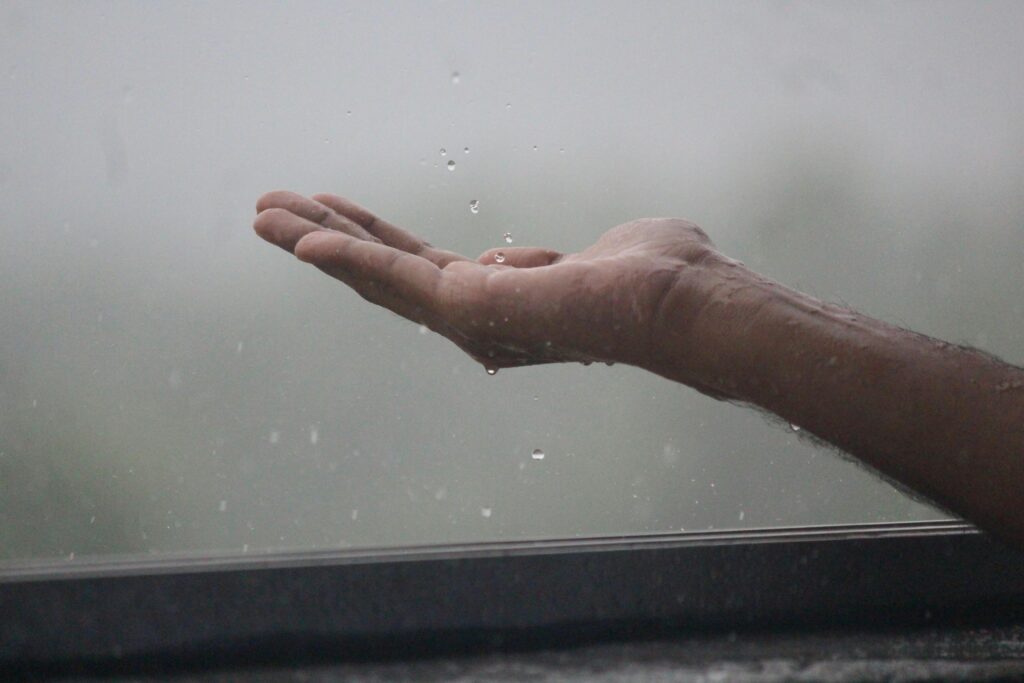 pexels-photo-12992553-12992553 Close-up of a hand reaching out to catch raindrops during a rain shower in Mangaluru, India.