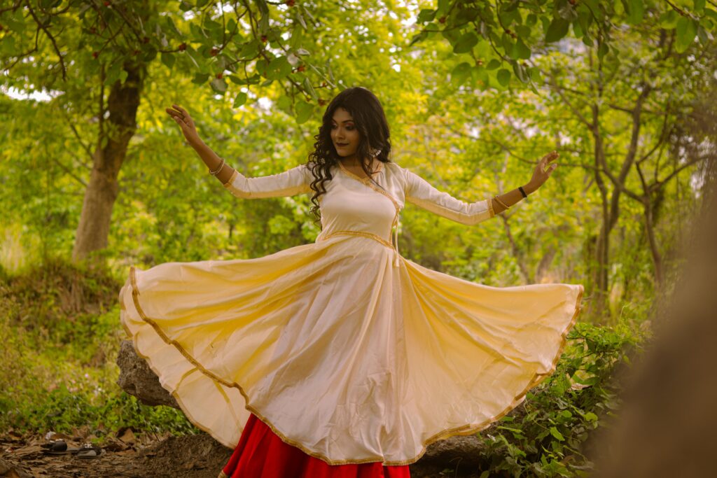 pexels-photo-31613163-31613163 Young woman performing a dance in traditional Indian attire in a lush, outdoor setting.