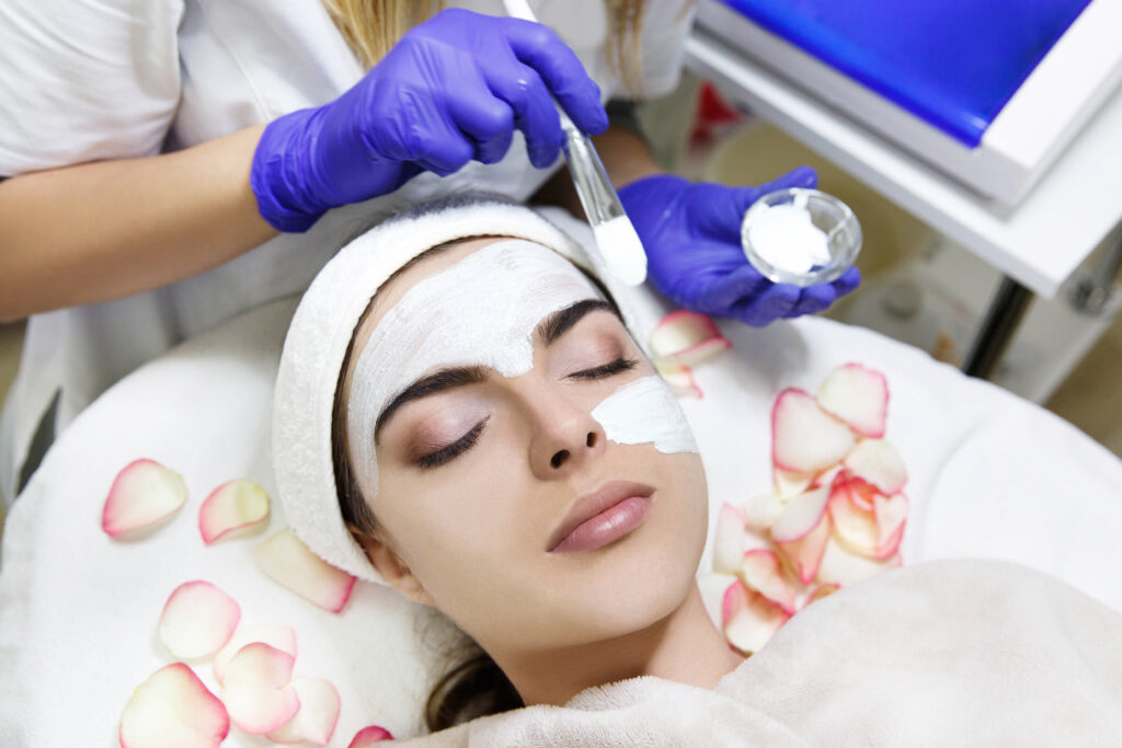 cosmetologiest applies white mask on woman's face cosmetologiest applies white mask on woman's face